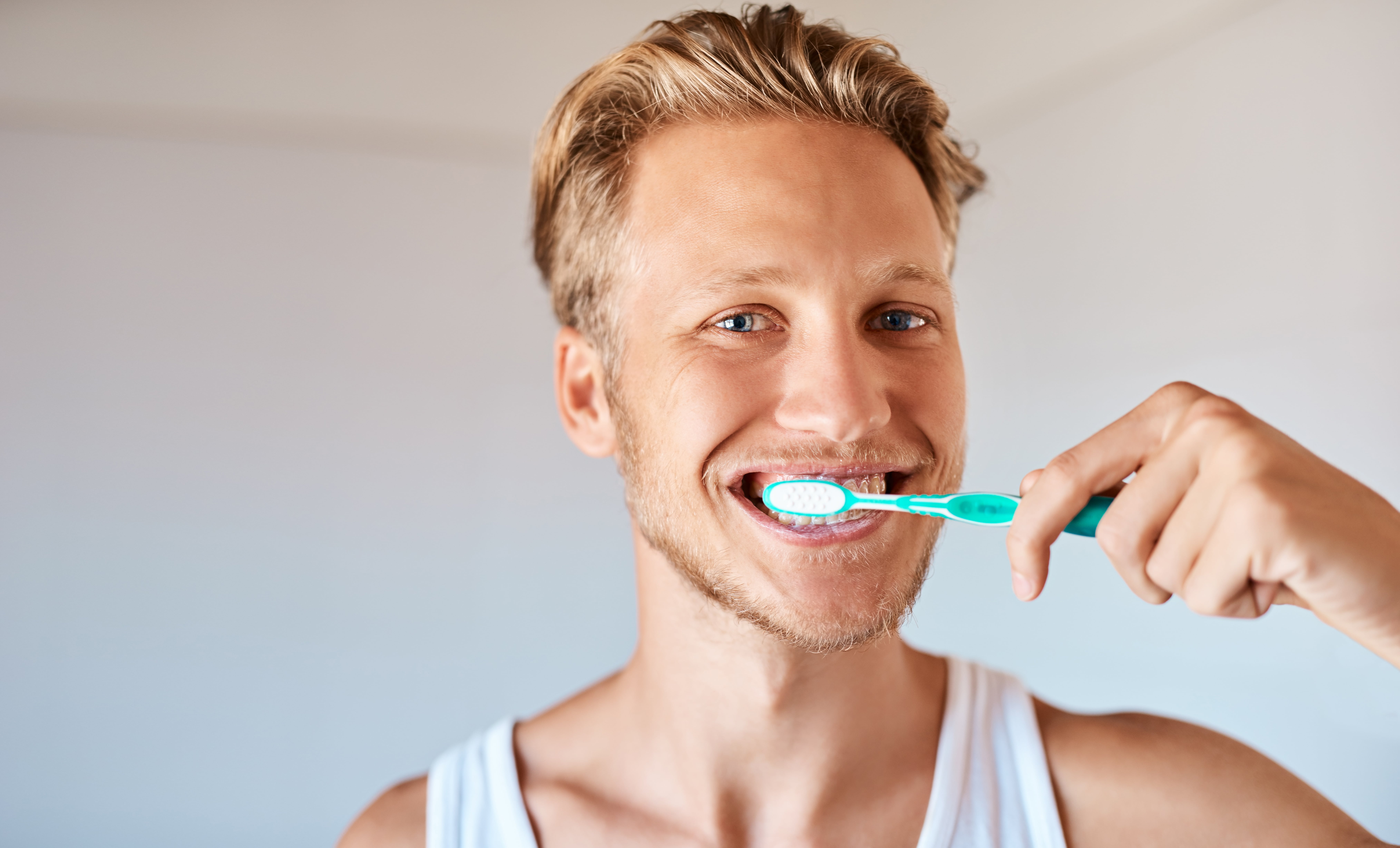 Young-blonde-man-brushing-his-teeth