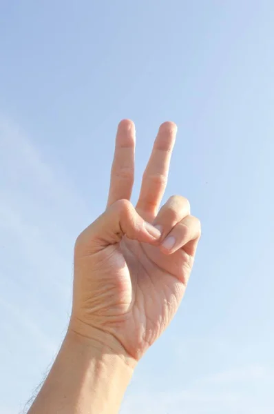 stock-photo-hand-two-fingers-victory-sign-blue-sky